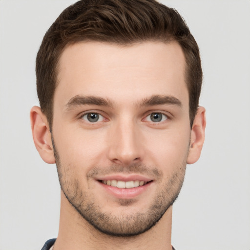 Joyful white young-adult male with short  brown hair and grey eyes