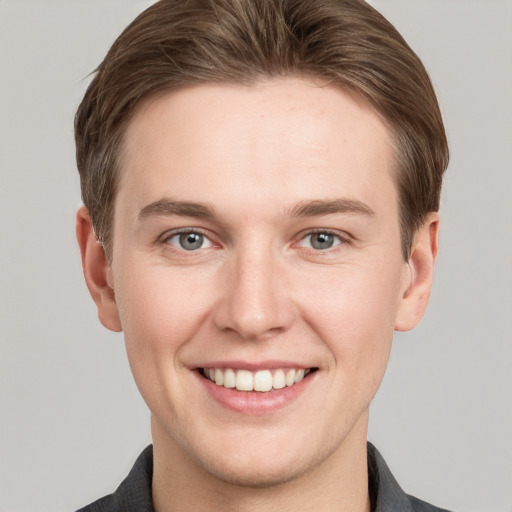 Joyful white young-adult male with short  brown hair and grey eyes