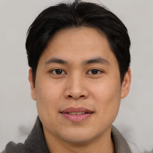 Joyful asian young-adult male with short  brown hair and brown eyes