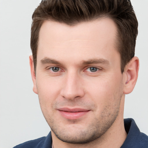 Joyful white young-adult male with short  brown hair and grey eyes