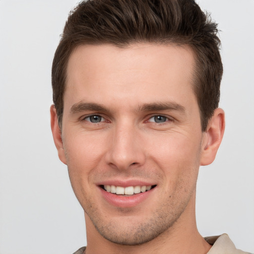 Joyful white young-adult male with short  brown hair and grey eyes