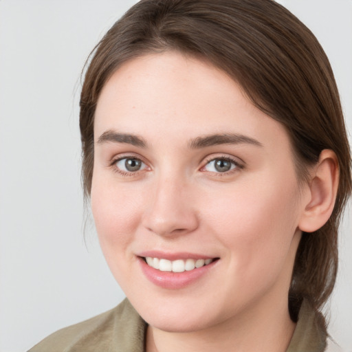 Joyful white young-adult female with medium  brown hair and grey eyes