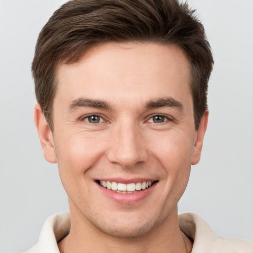 Joyful white young-adult male with short  brown hair and grey eyes