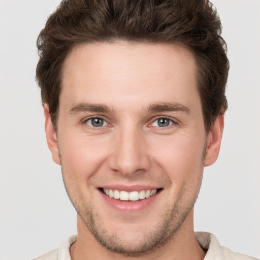 Joyful white young-adult male with short  brown hair and grey eyes