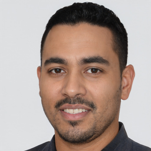 Joyful latino young-adult male with short  black hair and brown eyes
