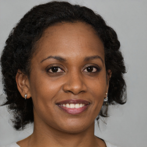 Joyful black young-adult female with medium  brown hair and brown eyes