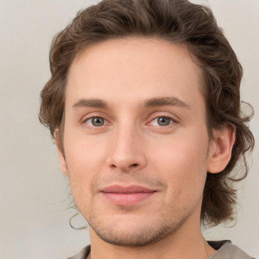 Joyful white young-adult male with medium  brown hair and green eyes