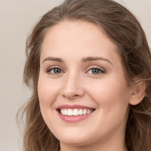 Joyful white young-adult female with long  brown hair and grey eyes