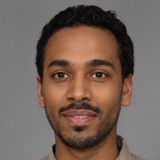 Joyful black young-adult male with short  black hair and brown eyes