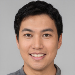 Joyful asian young-adult male with short  black hair and brown eyes