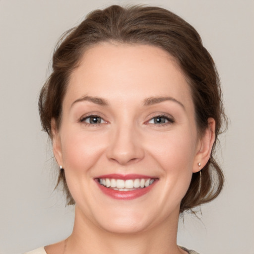 Joyful white young-adult female with medium  brown hair and grey eyes