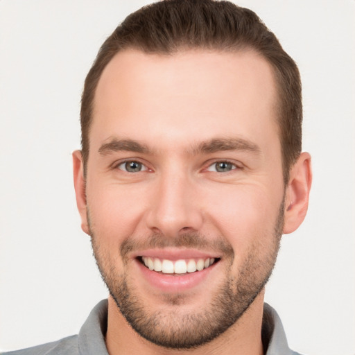 Joyful white young-adult male with short  brown hair and grey eyes