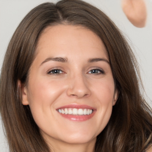 Joyful white young-adult female with long  brown hair and brown eyes