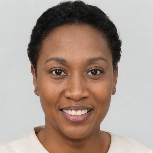 Joyful black young-adult female with short  black hair and brown eyes