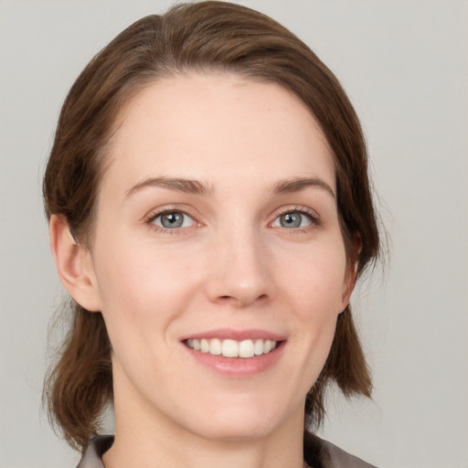 Joyful white young-adult female with medium  brown hair and grey eyes