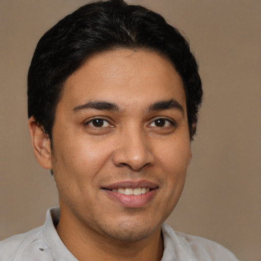 Joyful latino young-adult male with short  brown hair and brown eyes