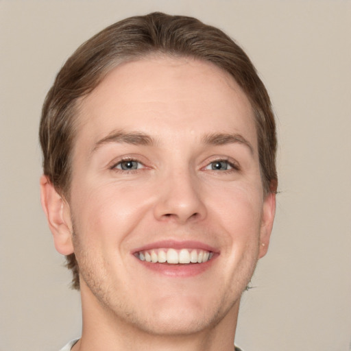 Joyful white young-adult male with short  brown hair and grey eyes