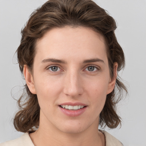 Joyful white young-adult female with medium  brown hair and grey eyes