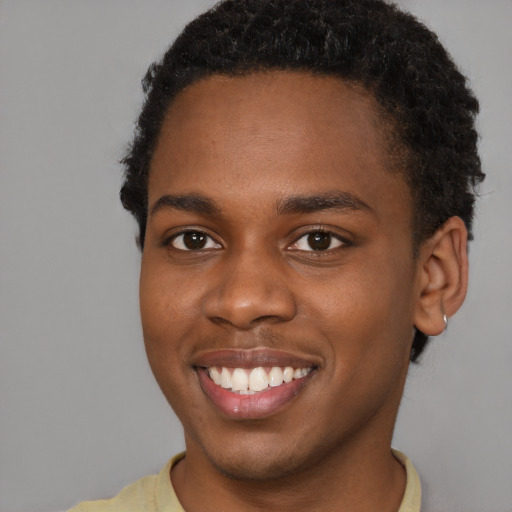 Joyful black young-adult male with short  brown hair and brown eyes