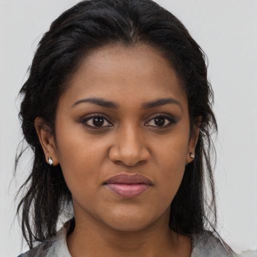 Joyful black young-adult female with long  brown hair and brown eyes