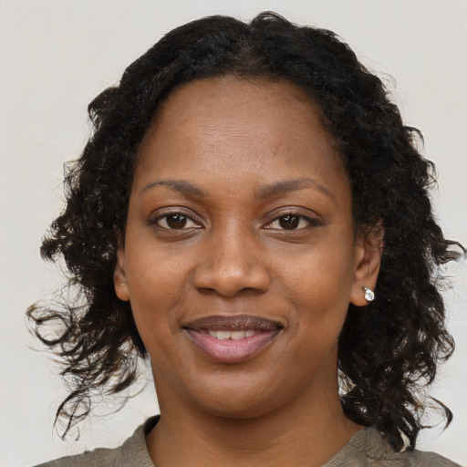 Joyful black adult female with long  brown hair and brown eyes