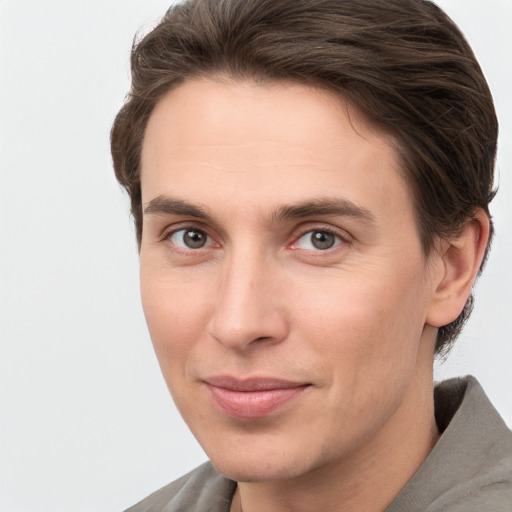 Joyful white young-adult male with short  brown hair and grey eyes