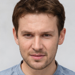 Joyful white young-adult male with short  brown hair and grey eyes