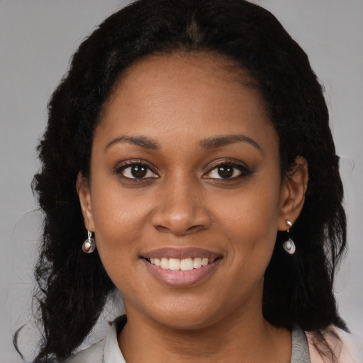 Joyful black young-adult female with long  brown hair and brown eyes