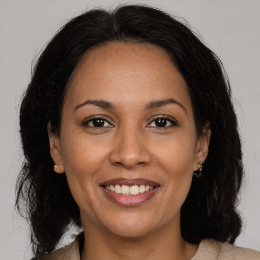 Joyful black adult female with long  brown hair and brown eyes