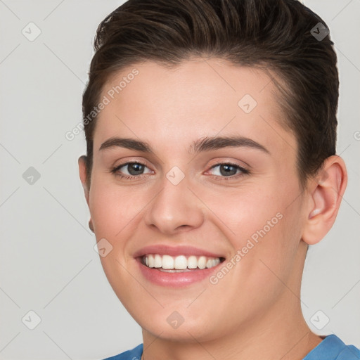 Joyful white young-adult female with short  brown hair and grey eyes