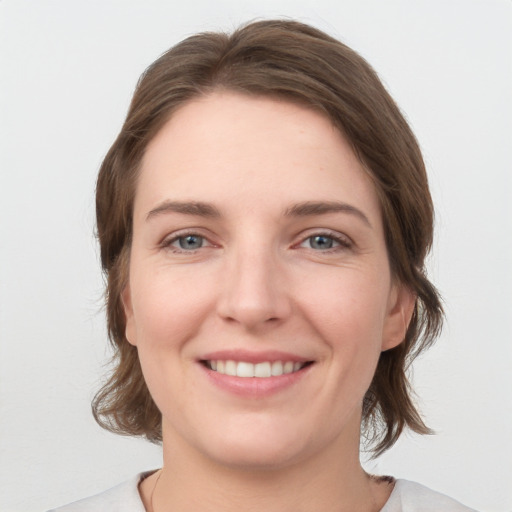 Joyful white young-adult female with medium  brown hair and grey eyes