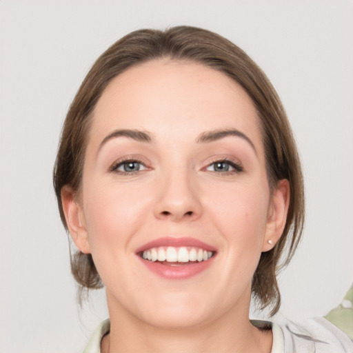 Joyful white young-adult female with medium  brown hair and grey eyes