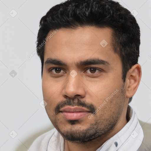 Joyful latino young-adult male with short  black hair and brown eyes