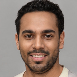 Joyful latino young-adult male with short  black hair and brown eyes