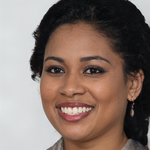 Joyful black young-adult female with long  black hair and brown eyes
