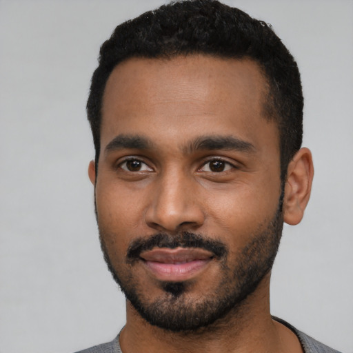 Joyful black young-adult male with short  black hair and brown eyes