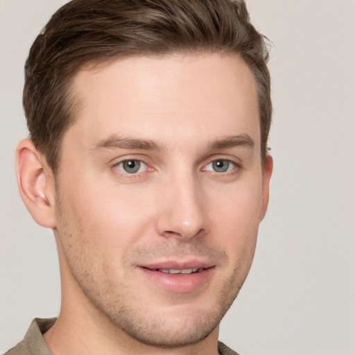 Joyful white young-adult male with short  brown hair and grey eyes