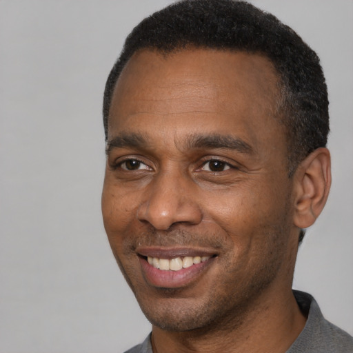 Joyful black young-adult male with short  brown hair and brown eyes