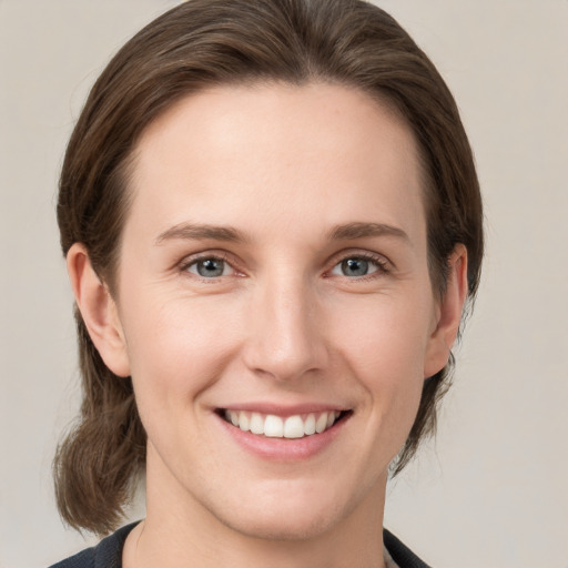 Joyful white young-adult female with medium  brown hair and grey eyes