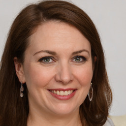 Joyful white adult female with long  brown hair and green eyes