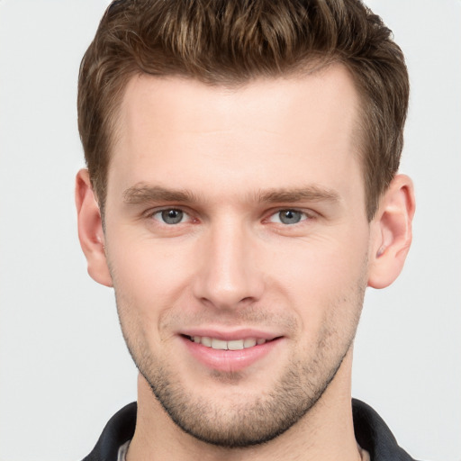 Joyful white young-adult male with short  brown hair and grey eyes