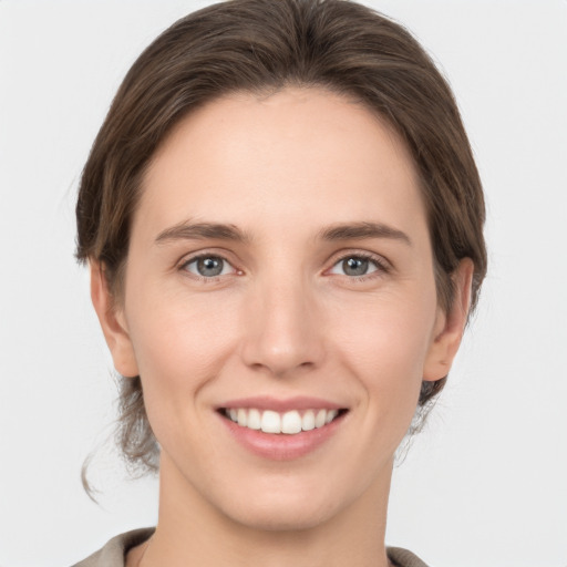 Joyful white young-adult female with medium  brown hair and grey eyes