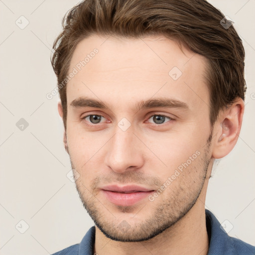 Joyful white young-adult male with short  brown hair and grey eyes