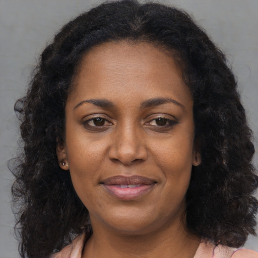 Joyful black young-adult female with long  brown hair and brown eyes