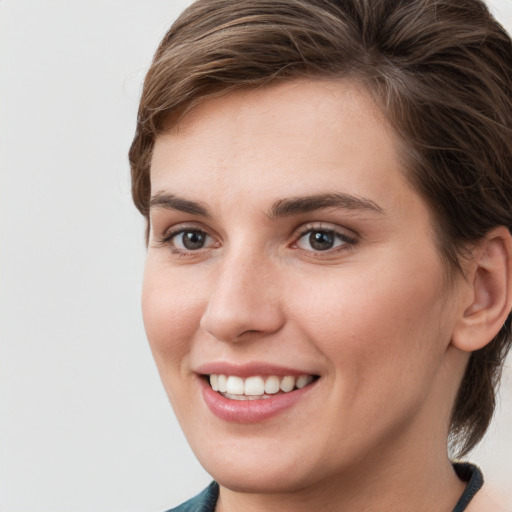 Joyful white young-adult female with medium  brown hair and grey eyes