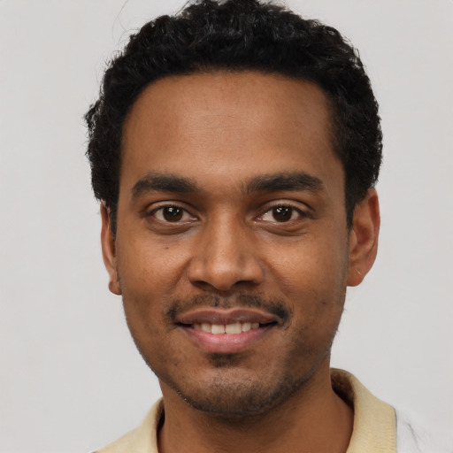 Joyful black young-adult male with short  black hair and brown eyes