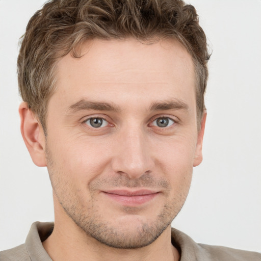 Joyful white young-adult male with short  brown hair and grey eyes