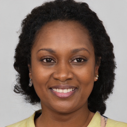 Joyful black young-adult female with long  brown hair and brown eyes