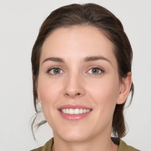 Joyful white young-adult female with medium  brown hair and green eyes