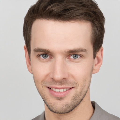 Joyful white young-adult male with short  brown hair and grey eyes